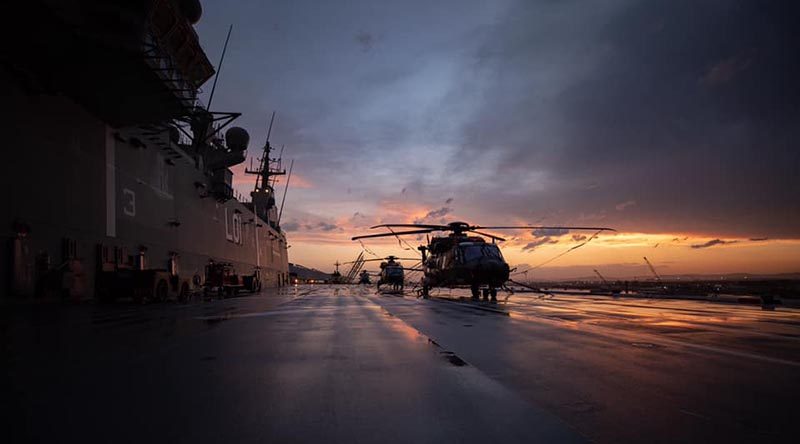 HMAS Adelaide and her embarked helicopters bask in a Solomon Islands sunset.