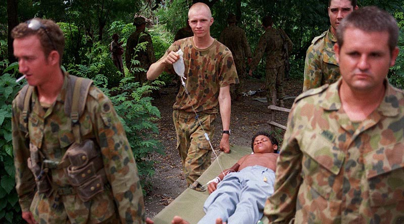 Australian soldiers with 3rd Battalion, Royal Australian Regiment, conduct a medical evacuation of a local boy in the Oecusse Enclave, East Timor. Photo by Corporal Brian Hartigan.