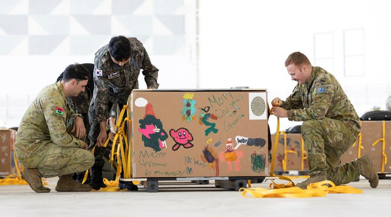 A member from the Republic of Korea Air Force, centre, helps Australian Army air dispatchers Corporal Ryan Cheevers and Private Kurt Matthews prepare a 'bundle' for Operation Christmas Drop 24. Story by Lieutenant Geoff Long. Photos by Leading Aircraftwoman Maddison Scott.