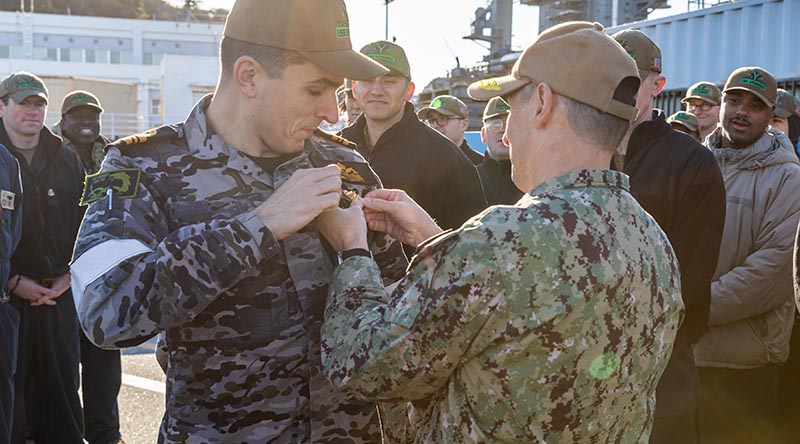 Rear Admiral Chris Cavanaugh, commander, Submarine Group 7, pins US Navy Submarine Warfare Device 'dolphins' on a Royal Australian Navy lieutenant commander during a pier-side quarters for the Virginia-class fast-attack submarine USS Vermont (SSN 792) in Japan. US Navy photo by Mass Communication Specialist 2nd Class Daniel G. Providakes.