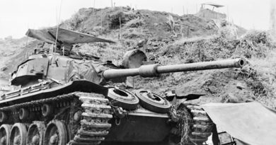 An Australian Centurion Mk V/1 tank of the 1st Armoured Regiment, Royal Australian Armoured Corps, guarding the approaches to the 1 Australian Task Force base located at Courtenay Hill. A hootchie has been set up over the turret as a sun screen and a sand bagged observation post is visible on the hill top. Photo by Brian Wood – AWM P07256.031
