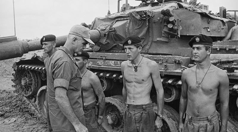 Corporal Bill Burton (far left) and colleagues from 1 Troop, C Squadron, 1st Armoured Regiment, RAAC, speak with General William Westmoreland, Commander, US Military Assistance Command Vietnam, about an enemy attack on Fire Support Base Coral. Photo by Kevin Thurgar – AWM file THU/68/0566/VN