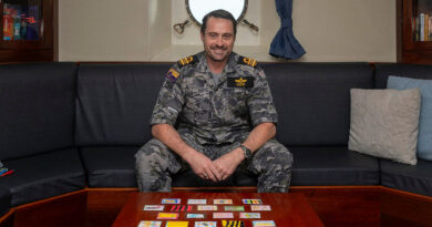 Lieutenant Commander Darcy Cook sits in the wardroom with patches gifted by preschoolers at Goodstart Child Care Centre Mangerton. Story by Lieutenant Marcus Middleton. Photos by Leading Seaman Zac Dingle.