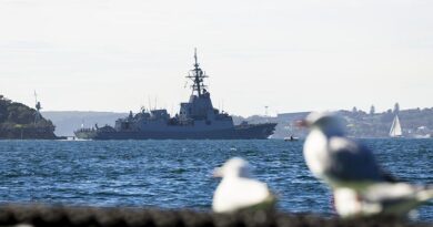 HMAS Sydney V sails past the mast of HMAS Sydney I as the ship departs for a Regional Presence Deployment, Sydney Harbour, NSW. Photo by Petty Officer David Cox.