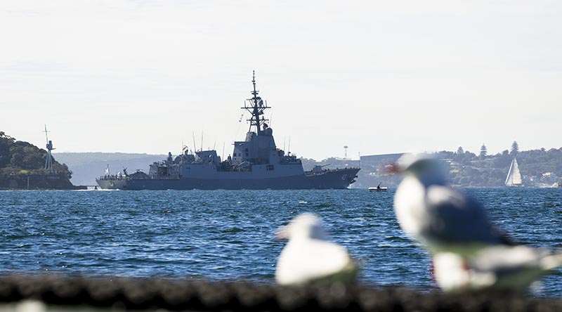 HMAS Sydney V sails past the mast of HMAS Sydney I as the ship departs for a Regional Presence Deployment, Sydney Harbour, NSW. Photo by Petty Officer David Cox.