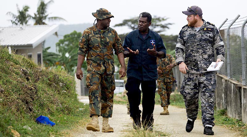 Vanuatu Mobile Force Lance Corporal Larry Qara, Royal Solomon Islands Police Force Explosive Ordnance Disposal Department Police Constable Barnabas Talo and Royal Australian Navy sailor, Leading Seaman Clearance Diver Bradley Fox discuss explosive ordnance disposal techniques at Cook Barracks in Port Vila, Vanuatu, during Operation Render Safe 26-2. Photo by Petty Officer Daniel Goodman.